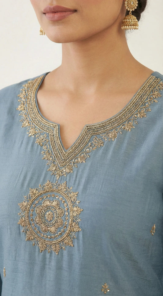Blue kurti with gold floral embroidery and V-neck, worn with traditional earrings