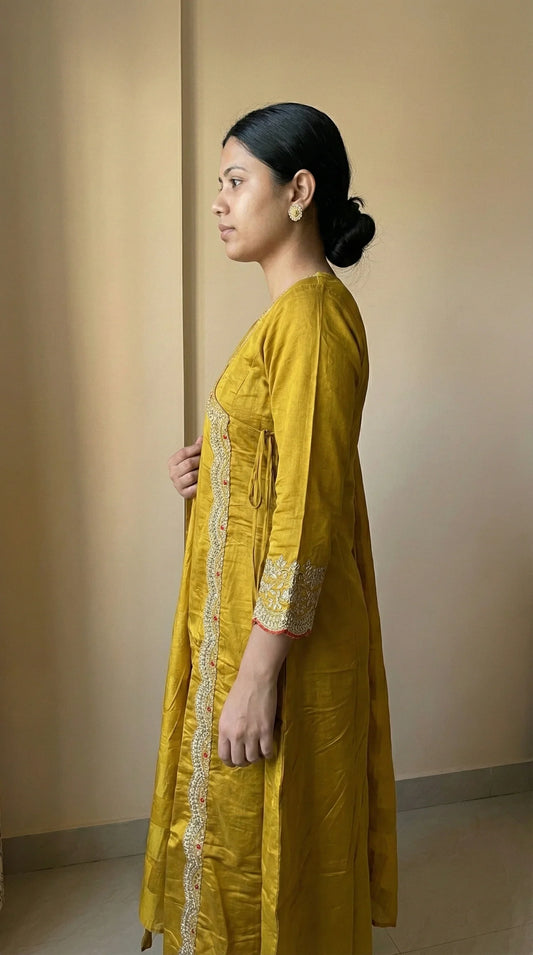 Woman in mustard yellow kurti with white embroidery, side profile, indoor setting